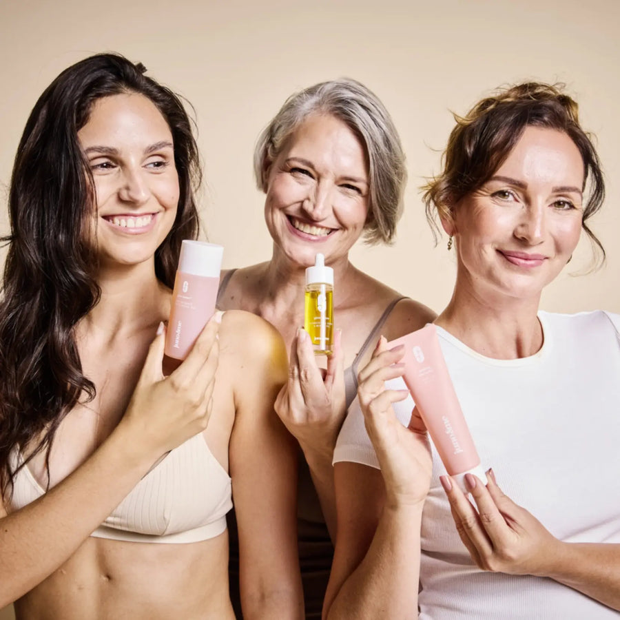 Drei lachende Frauen halten Peeling, Gel und Glow Below Oil