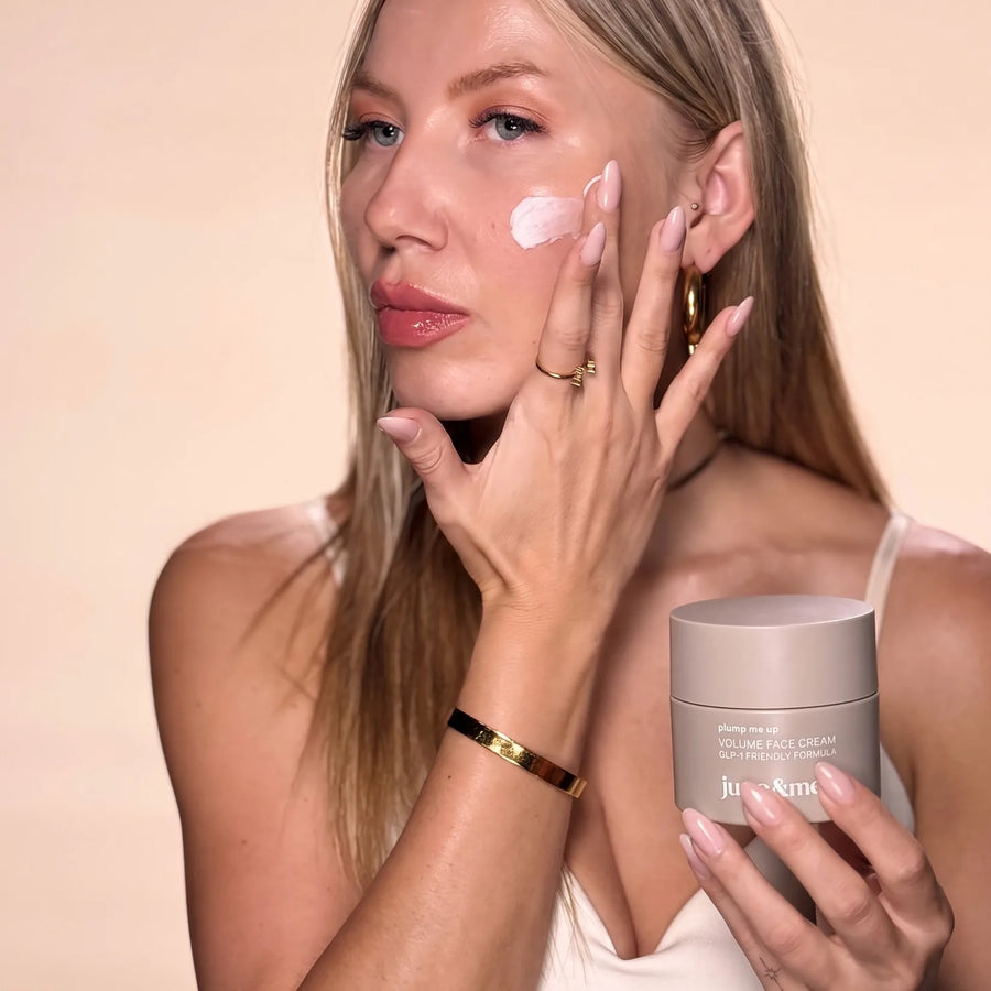 Frau trägt Volume Face Cream auf die Wange auf und hält den Tiegel