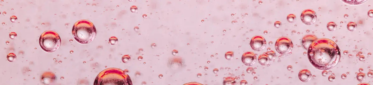 Transparente Rosa Flüssigkeit mit schwebenden Luftblasen.