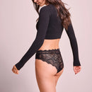 Frau trägt schwarze Periodenunterwäsche Cheeky-Lace mit schwarzem Oberteil.