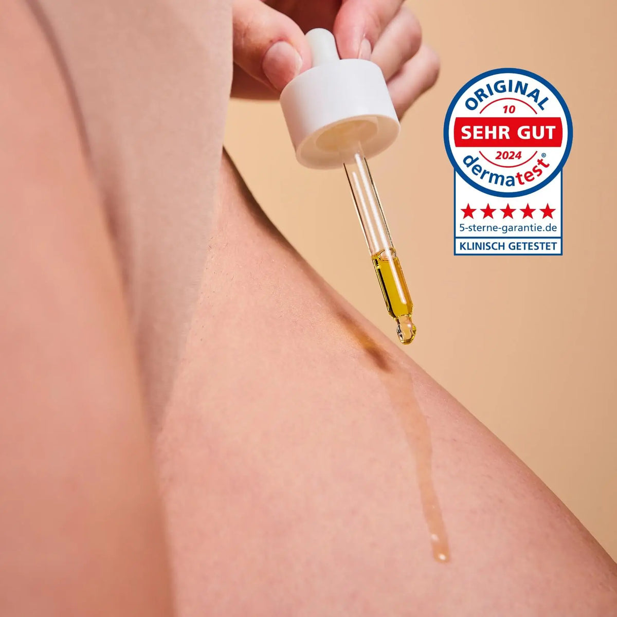 Glow Below Oil from the Glow Below Duo dripping onto skin, with the German Dermatest seal "sehr gut"