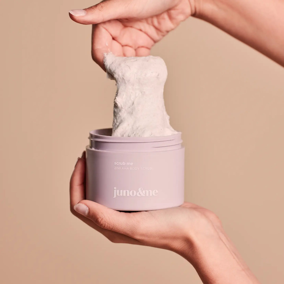 Hände halten den geöffneten 2in1 AHA Body Scrub aus dem Body Crush Trio und zeigen die Textur, juno&me