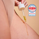 Glow Below Oil aus dem Happy Shaving Trio tropft aus der Pipette auf die Haut, daneben Dermatest-Siegel sehr gut