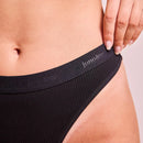 Schwarzer Panty wird von einer Hand am Bund gehalten.