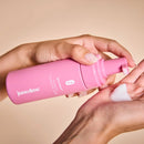 Frau hält rosa Intimate-Cleansing-Foam und schäumt Schaum auf die andere Hand.

