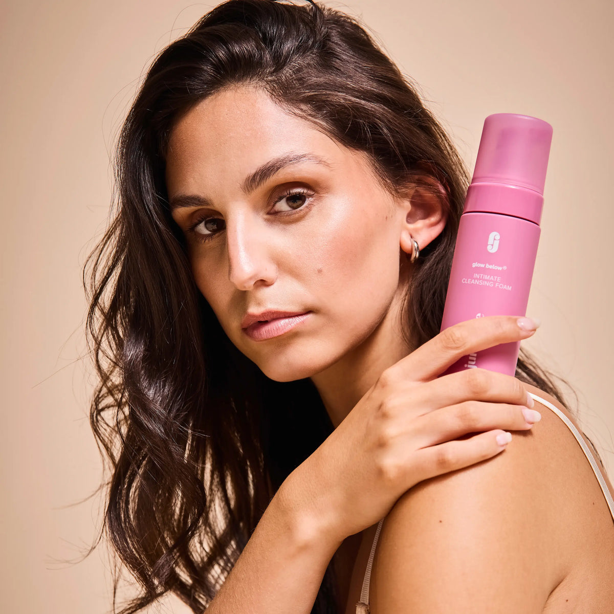 Frau hält Intimate-Cleansing-Foam auf ihrer Schulter und guckt in die Kamera.
