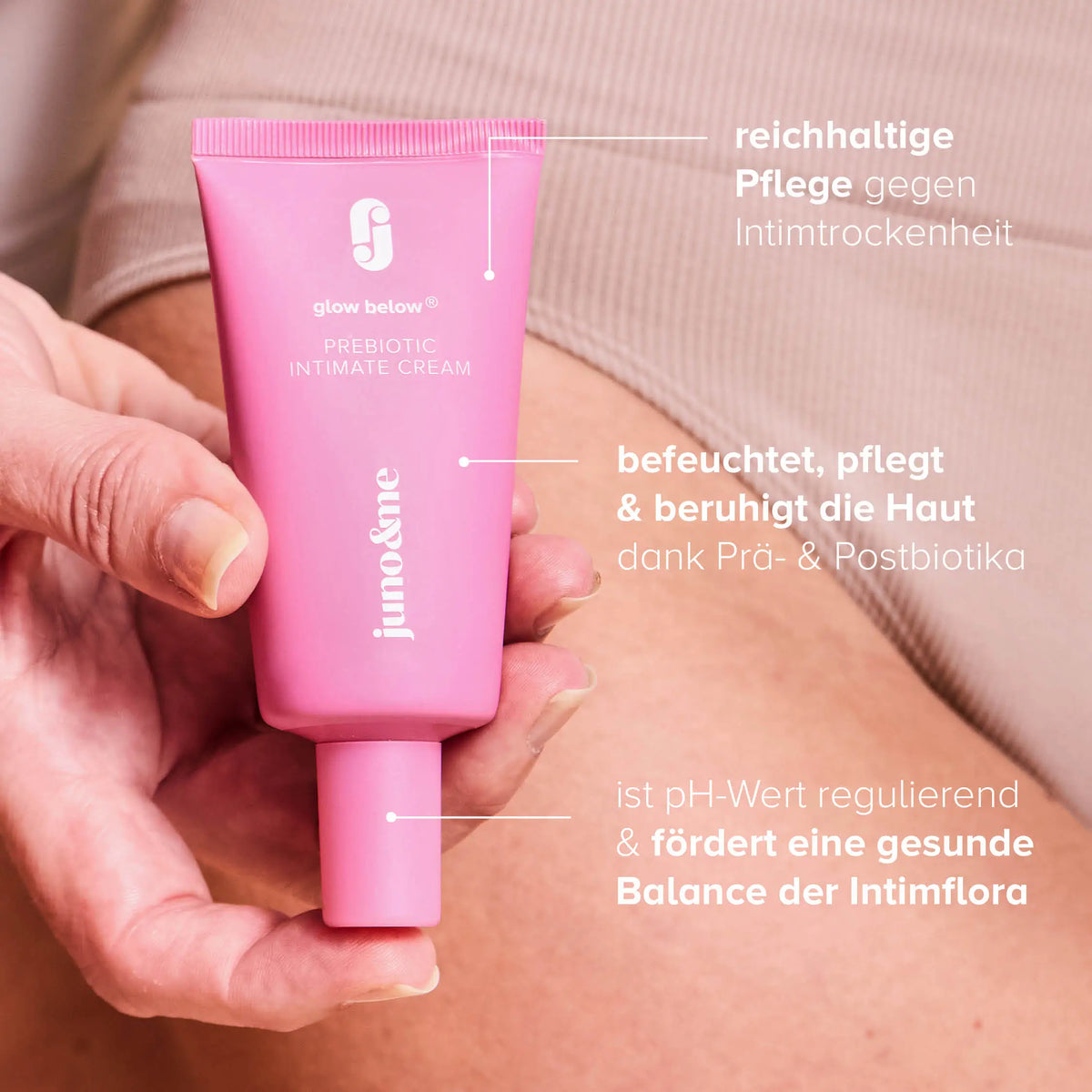 Rosafarbene Intimate-Prebiotic-Creme wird vor die Haut gehalten, mit Textfeldern.