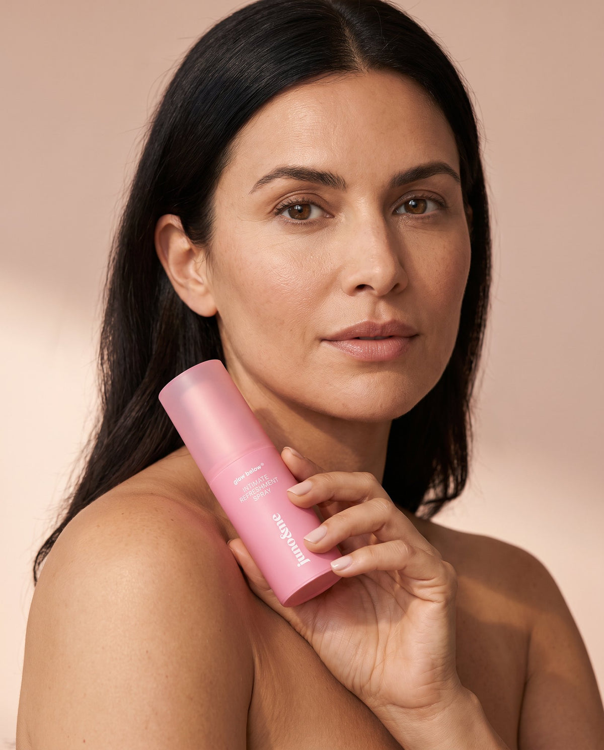 Dark-haired woman holding the Intim Deo by juno&me to her shoulder